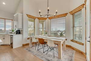 Dining area featuring plenty of natural light, a towering ceiling, an inviting chandelier, and light wood-type flooring