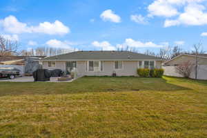 Back of property with a fire pit, a yard, and a patio area