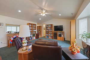 Carpeted living room featuring ceiling fan and vaulted ceiling