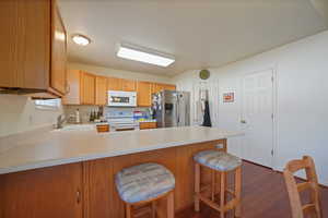 Kitchen with white appliances, kitchen peninsula, and door to the garage.