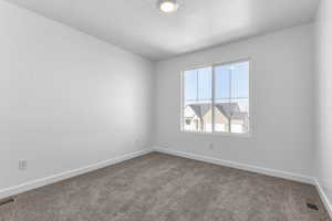 Carpeted spare room with visible vents, a textured ceiling, and baseboards