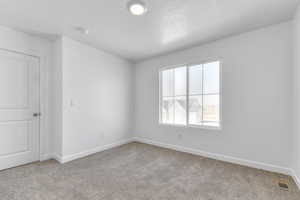 Empty room with visible vents, light carpet, baseboards, and a textured ceiling