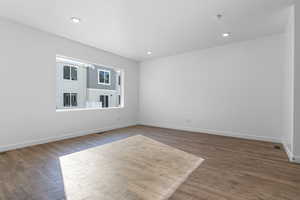 Spare room featuring dark wood-type flooring, recessed lighting, and baseboards