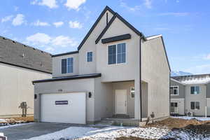 View of front facade with a garage, concrete driveway, and stucco siding