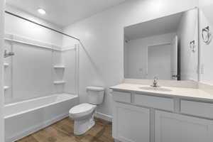 Bathroom featuring baseboards, toilet, shower / tub combination, wood finished floors, and vanity