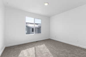 Carpeted spare room with visible vents and baseboards