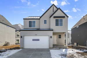 View of front facade with a garage, concrete driveway, and stucco siding