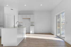 Kitchen with visible vents, white cabinets, light wood-style floors, a sink, and recessed lighting