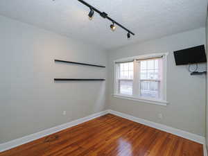 Spare room with hardwood / wood-style flooring, a textured ceiling, and track lighting