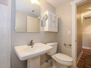 Bathroom featuring toilet, a textured ceiling, and sink