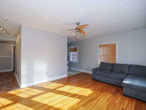 Unfurnished living room featuring ceiling fan, hardwood / wood-style floors, washer / dryer, and a textured ceiling