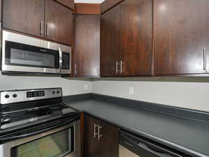 Kitchen with appliances with stainless steel finishes and dark brown cabinets