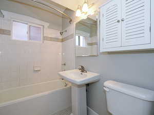 Full bathroom with toilet, tiled shower / bath combo, and sink