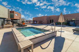 View of swimming pool with a hot tub and a patio