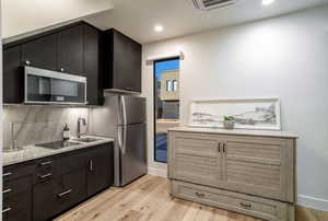 Kitchen featuring sink, stainless steel appliances, light wood-type flooring, and decorative backsplash