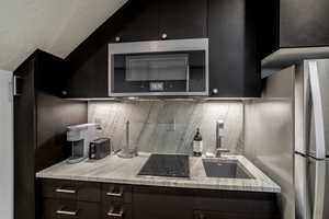 Kitchen with light stone counters, stainless steel appliances, backsplash, and sink