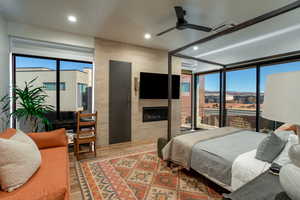 Bedroom featuring a tile fireplace, multiple windows, ceiling fan, and hardwood / wood-style flooring