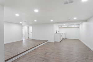 Basement with sink and light wood-type flooring