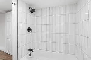 Bathroom featuring hardwood / wood-style floors and tiled shower / bath combo