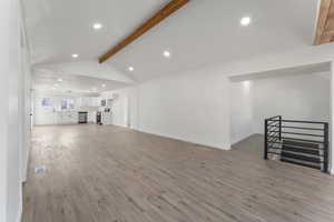 Living room with light wood-type flooring and vaulted ceiling with beams