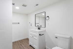 Bathroom with hardwood / wood-style floors, vanity, and toilet