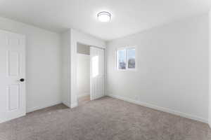 Unfurnished bedroom with light colored carpet and a closet