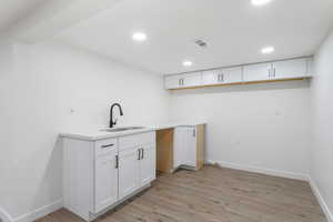 Clothes washing area featuring light hardwood / wood-style floors and sink