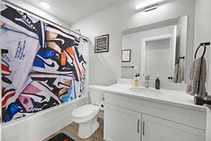 Full bathroom with toilet, vanity, shower / bath combo, and hardwood / wood-style flooring