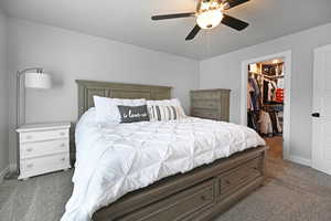 Carpeted bedroom with ceiling fan, a spacious closet, and a closet