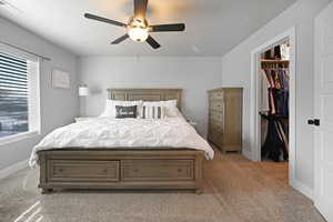 Bedroom featuring a spacious closet, a closet, ceiling fan, and light carpet