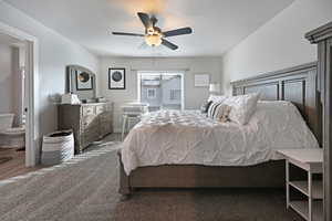 Carpeted bedroom with ceiling fan, a textured ceiling, and ensuite bath