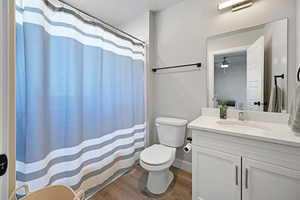 Bathroom with ceiling fan, toilet, wood-type flooring, and vanity