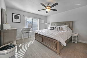 Carpeted bedroom with a textured ceiling and ceiling fan