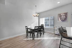 Dining room with a chandelier, a textured ceiling, and light hardwood / wood-style floors