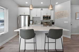 Kitchen featuring a kitchen island with sink, white cabinetry, and stainless steel appliances