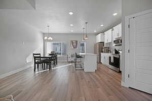 Kitchen with a kitchen breakfast bar, a kitchen island, stainless steel appliances, and decorative light fixtures