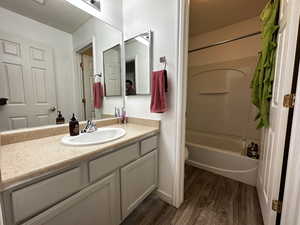 Full bathroom with a textured ceiling, vanity, shower / washtub combination, hardwood / wood-style flooring, and toilet