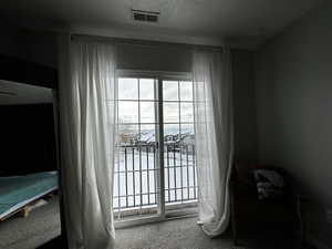 Doorway to outside featuring carpet and a textured ceiling