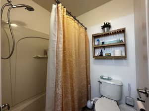 Bathroom with a textured ceiling and toilet