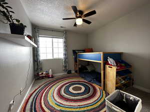 Bedroom featuring carpet flooring, ceiling fan, and a textured ceiling