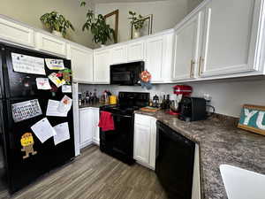 Kitchen with sink, white cabinets, black appliances, and wood-type flooring