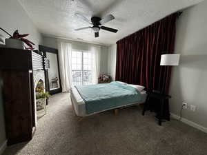 Carpeted bedroom featuring ceiling fan and a textured ceiling