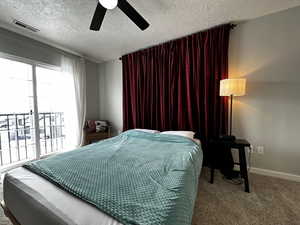 Bedroom with carpet, ceiling fan, access to exterior, and a textured ceiling