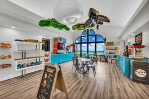 Recreation room with hardwood / wood-style floors, high vaulted ceiling, ceiling fan, and a water view