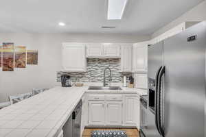 Kitchen featuring white cabinets, appliances with stainless steel finishes, and tile counters