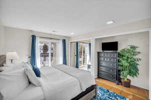 Bedroom with a textured ceiling, tile patterned floors, and access to exterior