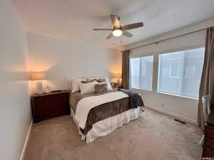 Bedroom with ceiling fan, light carpet, and a textured ceiling