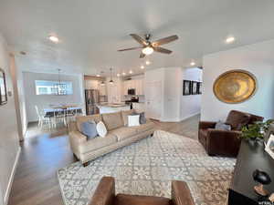 Living room with ceiling fan with notable chandelier, wood-type flooring, a textured ceiling, and sink