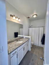 Full bathroom featuring toilet, a textured ceiling, tile patterned flooring, shower / bath combo with shower curtain, and vanity