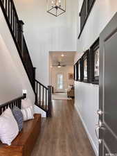 Entryway with ceiling fan with notable chandelier, a towering ceiling, and dark hardwood / wood-style floors